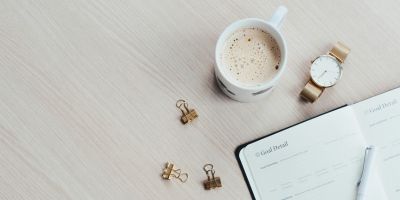 A cup of coffee and notepad lying on a table