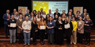 Winners of the research impact awards smile at the camera.
